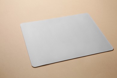 Photo of One mouse pad on beige background, closeup. Space for text