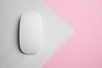 Photo of One wireless mouse with mousepad on pink background, top view. Space for text
