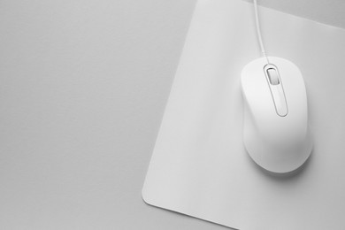 Wired mouse with mousepad on grey background, top view. Space for text