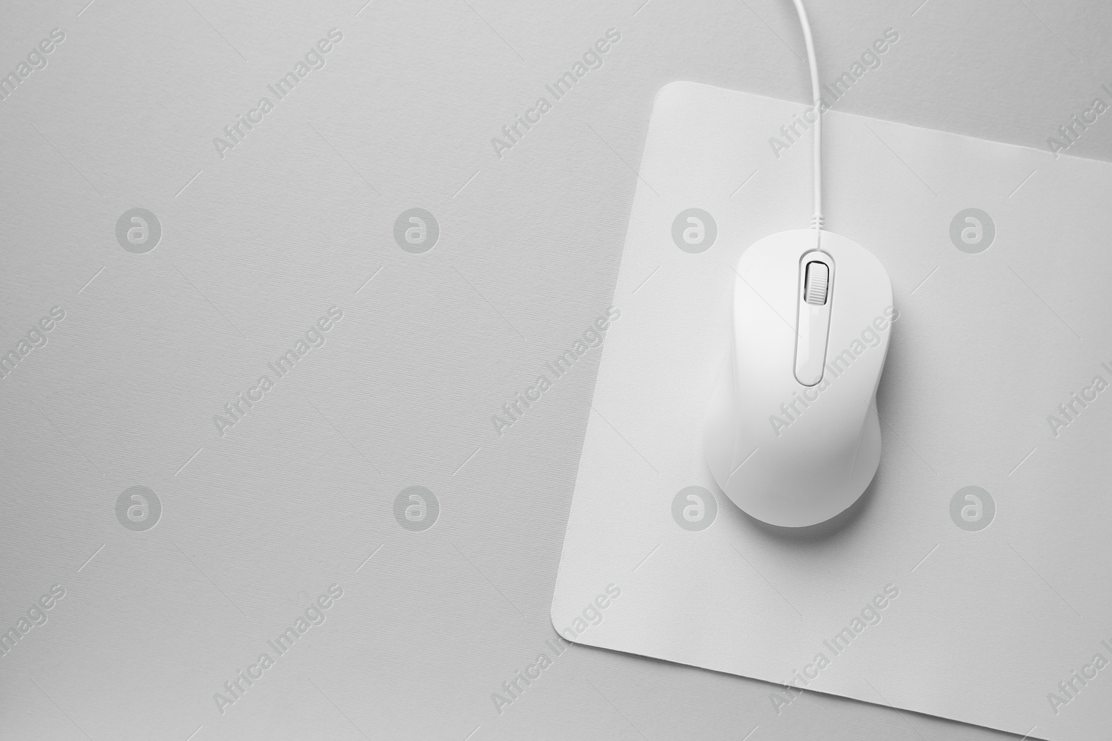 Photo of Wired mouse with mousepad on grey background, top view. Space for text