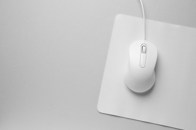 Photo of Wired mouse with mousepad on grey background, top view. Space for text