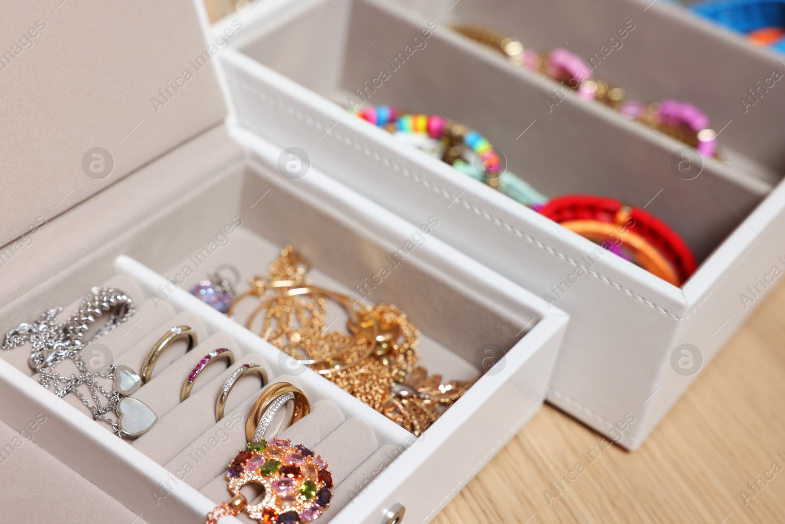 Photo of Jewelry boxes with stylish bracelets and other accessories on wooden table, closeup