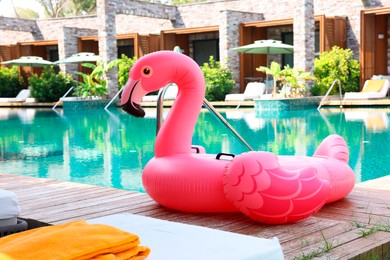 Float in shape of flamingo on wooden deck near swimming pool at luxury resort