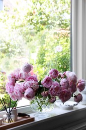 Photo of Beautiful pink peonies in vase on window sill, space for text. Interior design