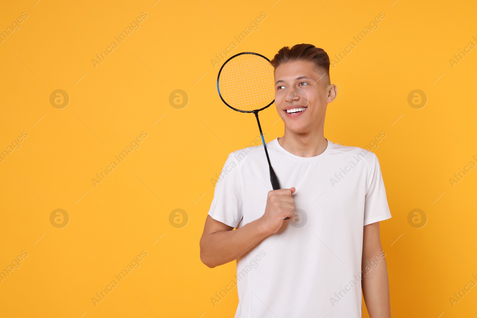 Photo of Young man with badminton racket on orange background