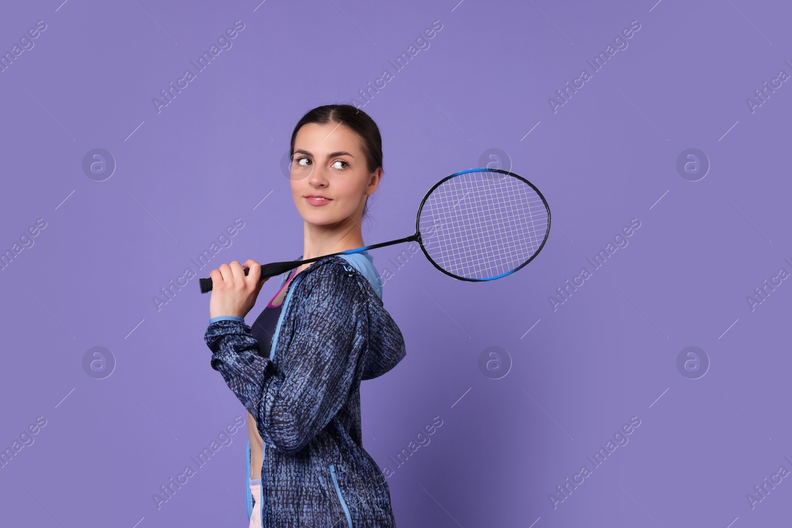 Photo of Young woman with badminton racket on purple background, space for text