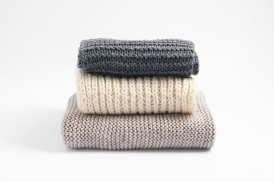 Photo of Stack of knitted scarfs on white background