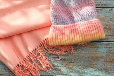 Photo of Soft scarf and knitted hat on wooden table, top view