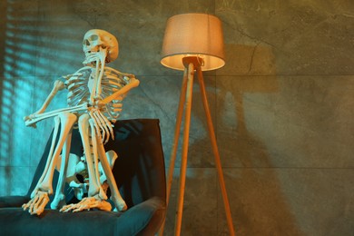 Photo of Waiting concept. Human skeleton sitting in armchair indoors, space for text