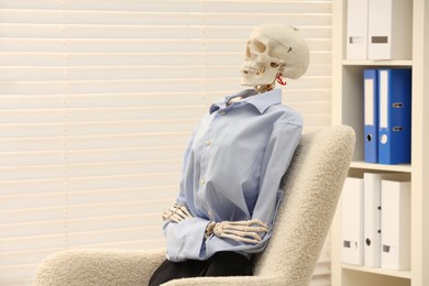 Photo of Waiting concept. Human skeleton sitting in armchair at office, space for text