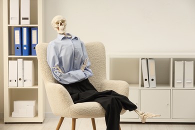 Photo of Waiting concept. Human skeleton sitting in armchair at office, space for text