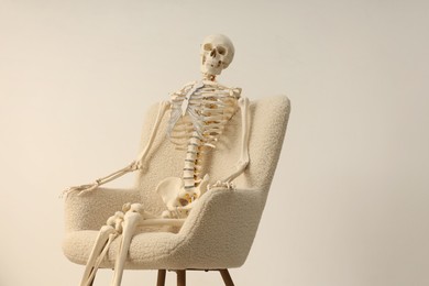 Photo of Waiting concept. Human skeleton sitting in armchair indoors, space for text