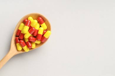 Photo of Many antibiotic pills with wooden spoon and space for text on grey background, top view. Medicinal treatment