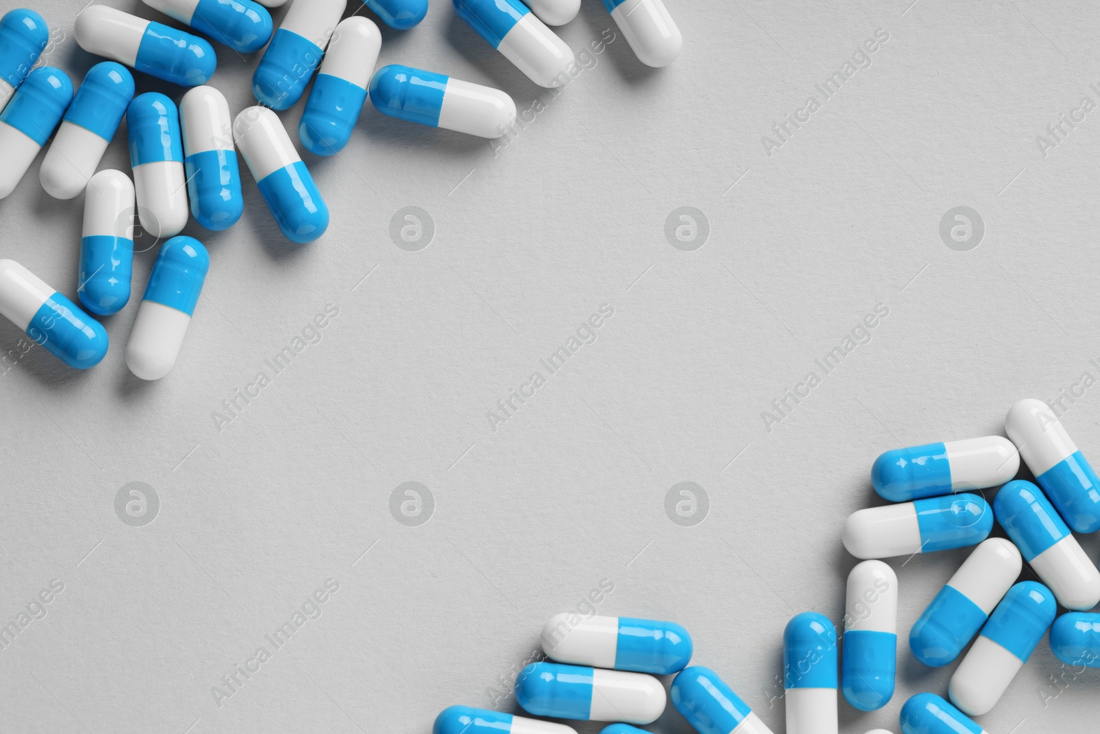 Photo of Many antibiotic pills on grey background, top view and space for text. Medicinal treatment