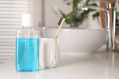 Bottle of mouthwash and toothbrush on white countertop in bathroom