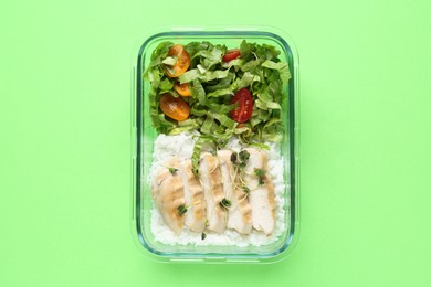 Photo of Healthy meal. Fresh salad, rice and chicken in glass container on green background, top view