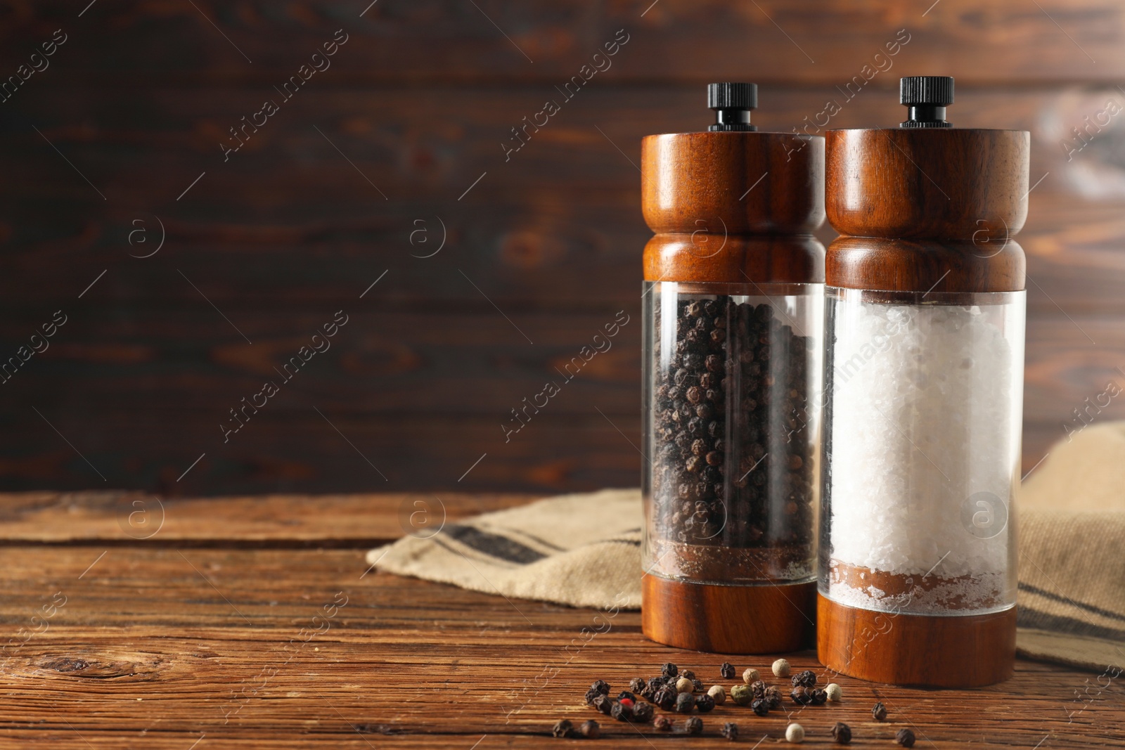 Photo of Salt and pepper shakers on wooden table, space for text