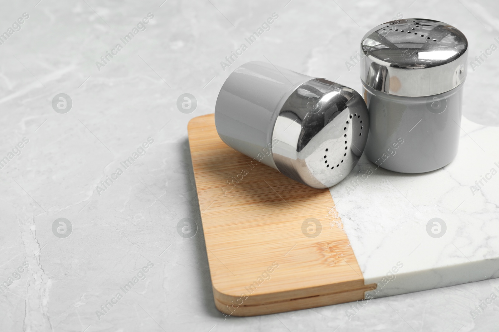 Photo of Salt and pepper shakers on grey marble table, space for text