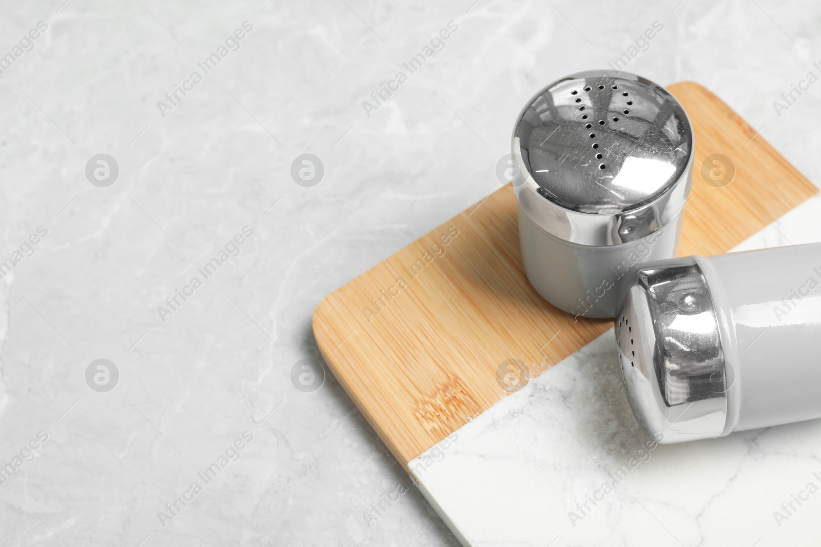 Photo of Salt and pepper shakers on grey marble table, space for text