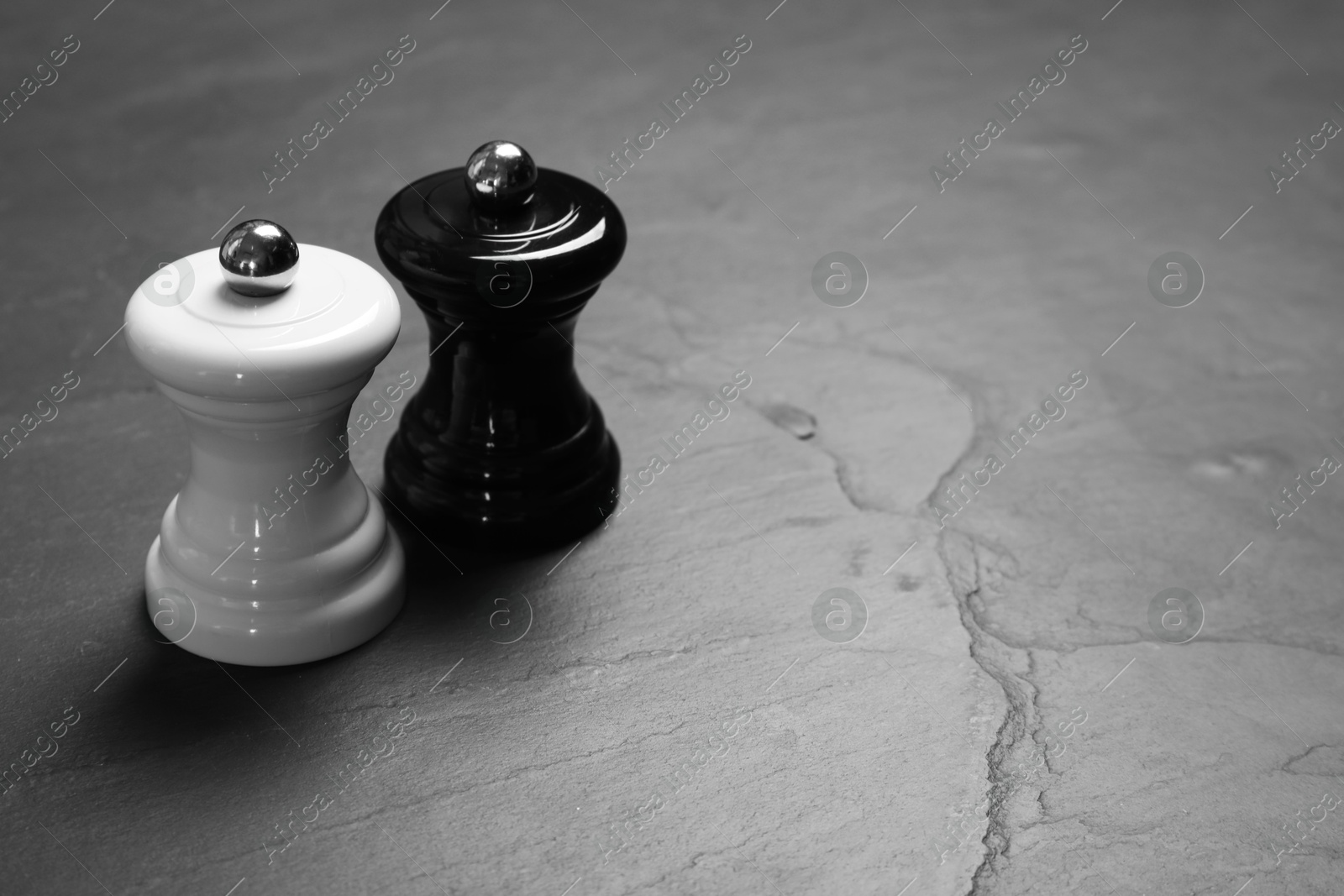 Photo of Salt and pepper shakers on grey textured table, space for text