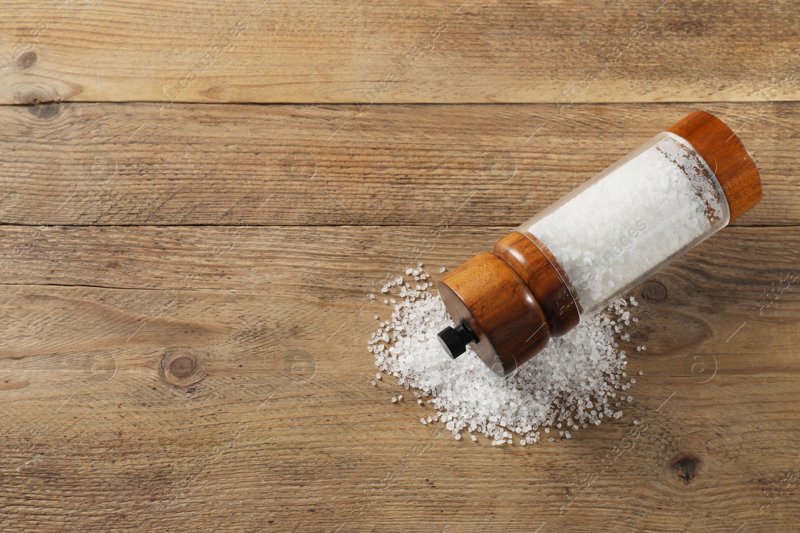 Photo of Salt shaker on wooden table, top view. Space for text