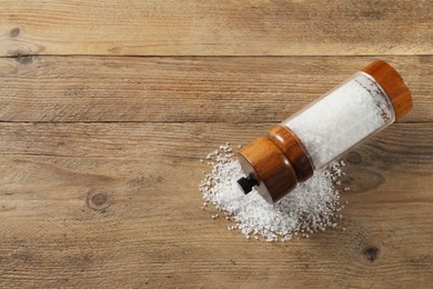 Photo of Salt shaker on wooden table, top view. Space for text