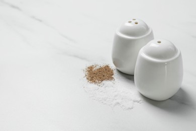 Salt and pepper shakers on white marble table, space for text