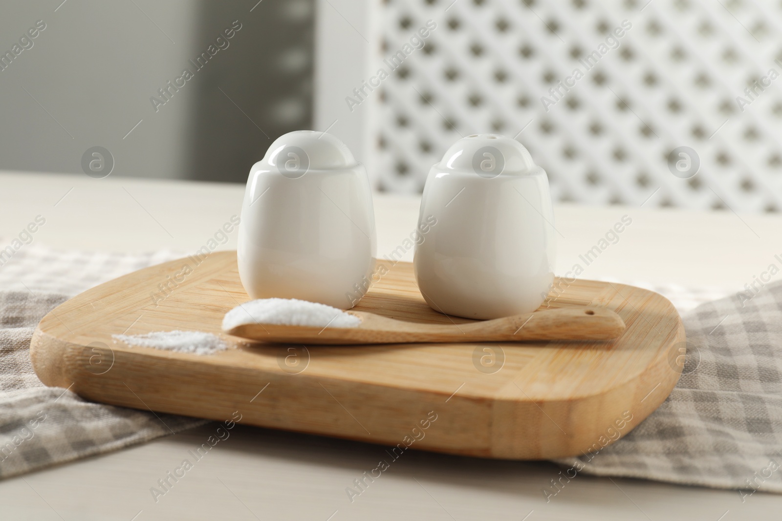 Photo of Spice shakers with salt on white wooden table