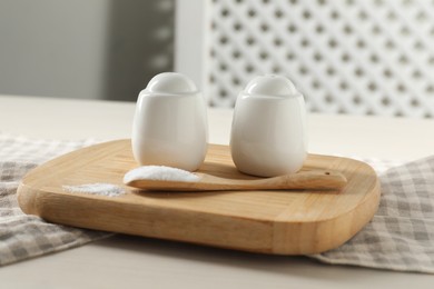 Spice shakers with salt on white wooden table