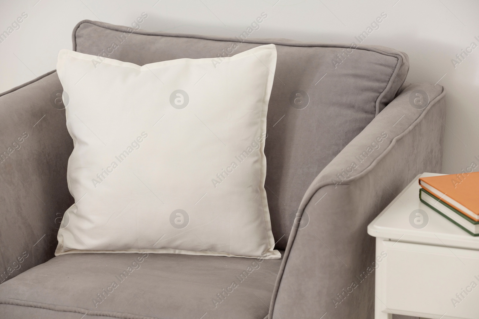 Photo of Soft white pillow on armchair near light wall indoors