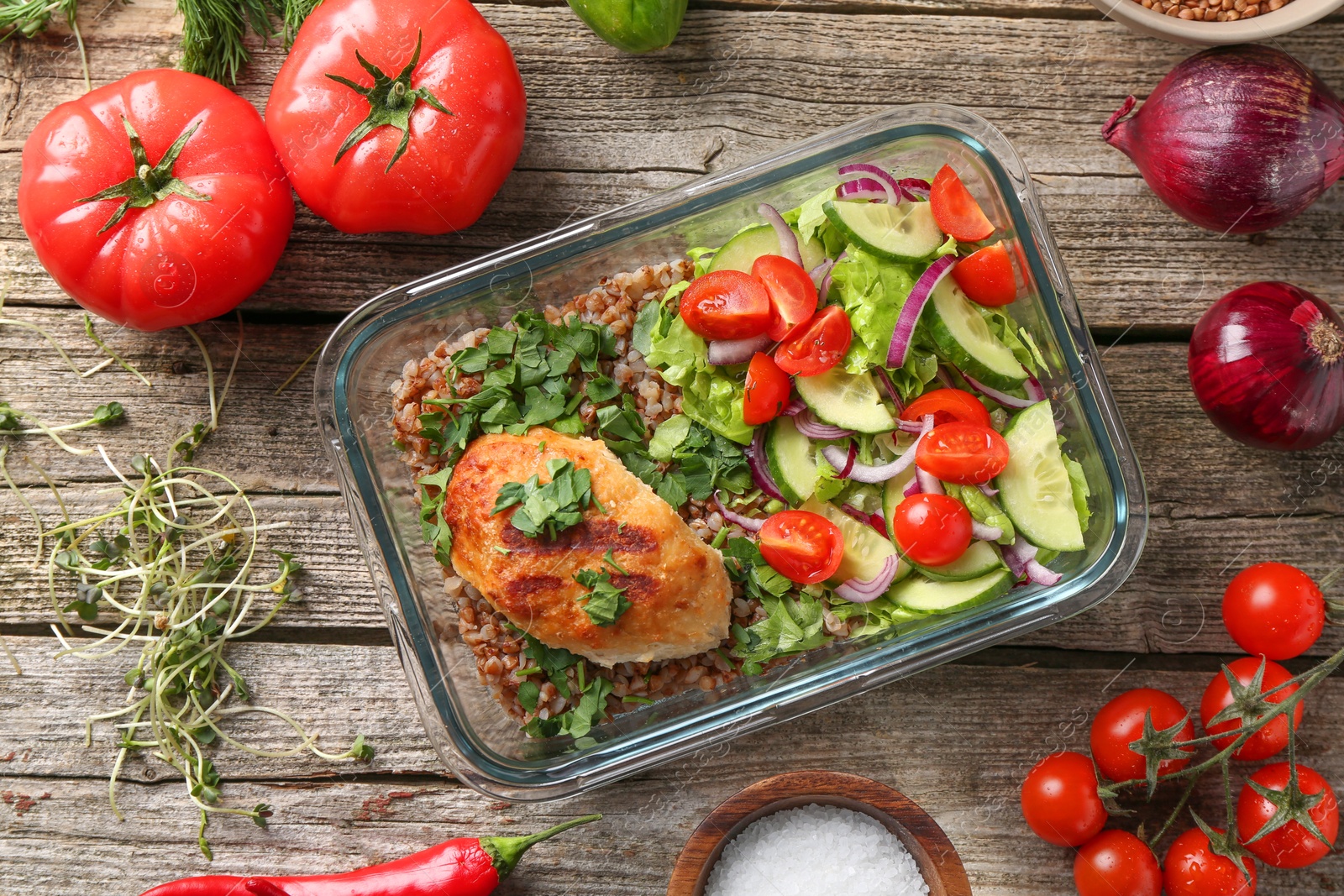 Photo of Healthy meal. Cutlet, buckwheat and salad in container near other products on wooden table, flat lay