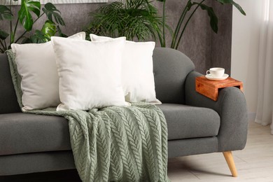 Photo of Soft white pillows and blanket on sofa indoors