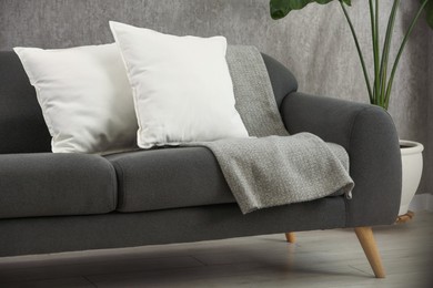 Photo of Soft white pillows and blanket on sofa indoors