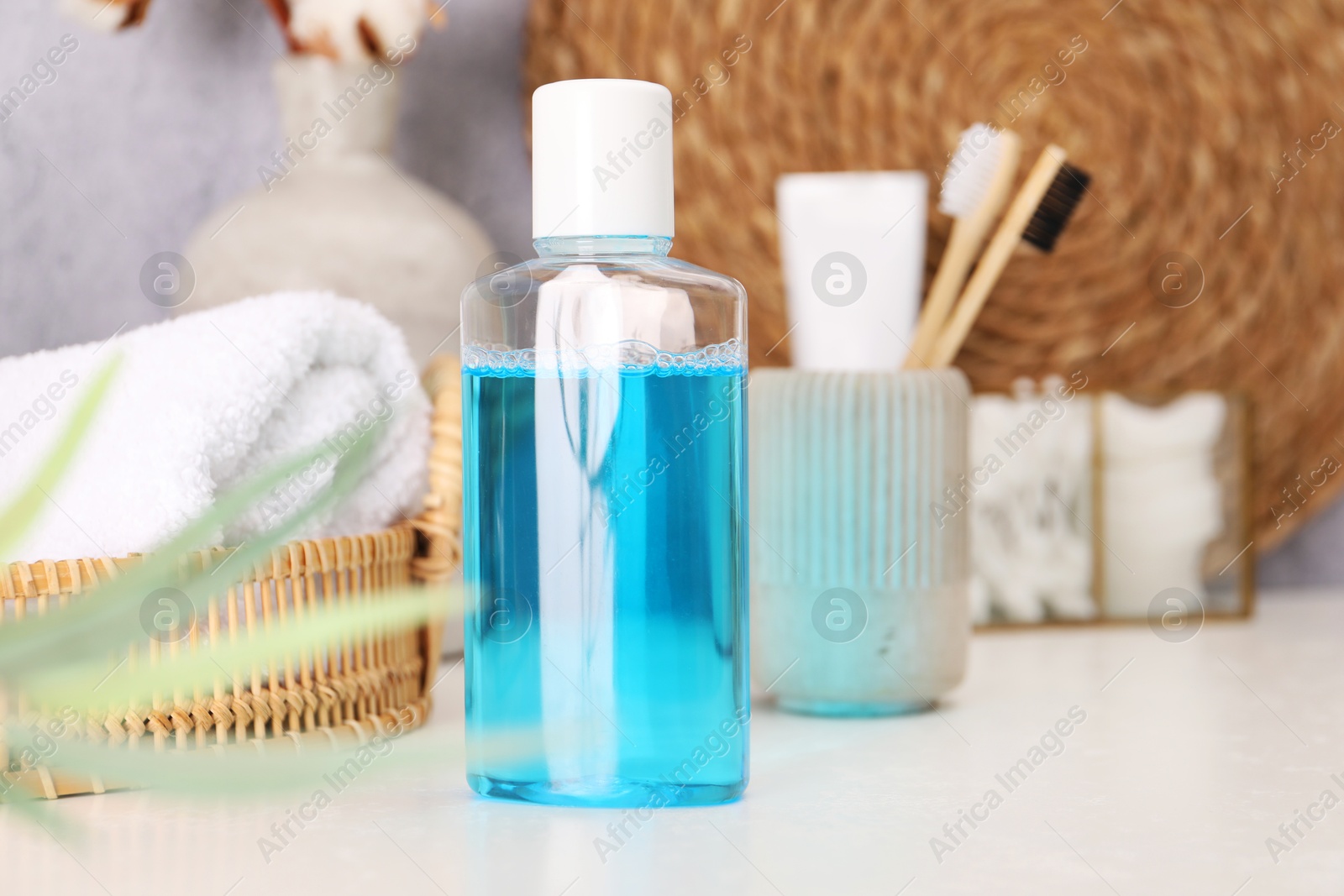 Photo of Bottle of mouthwash and toothbrushes on white table in bathroom