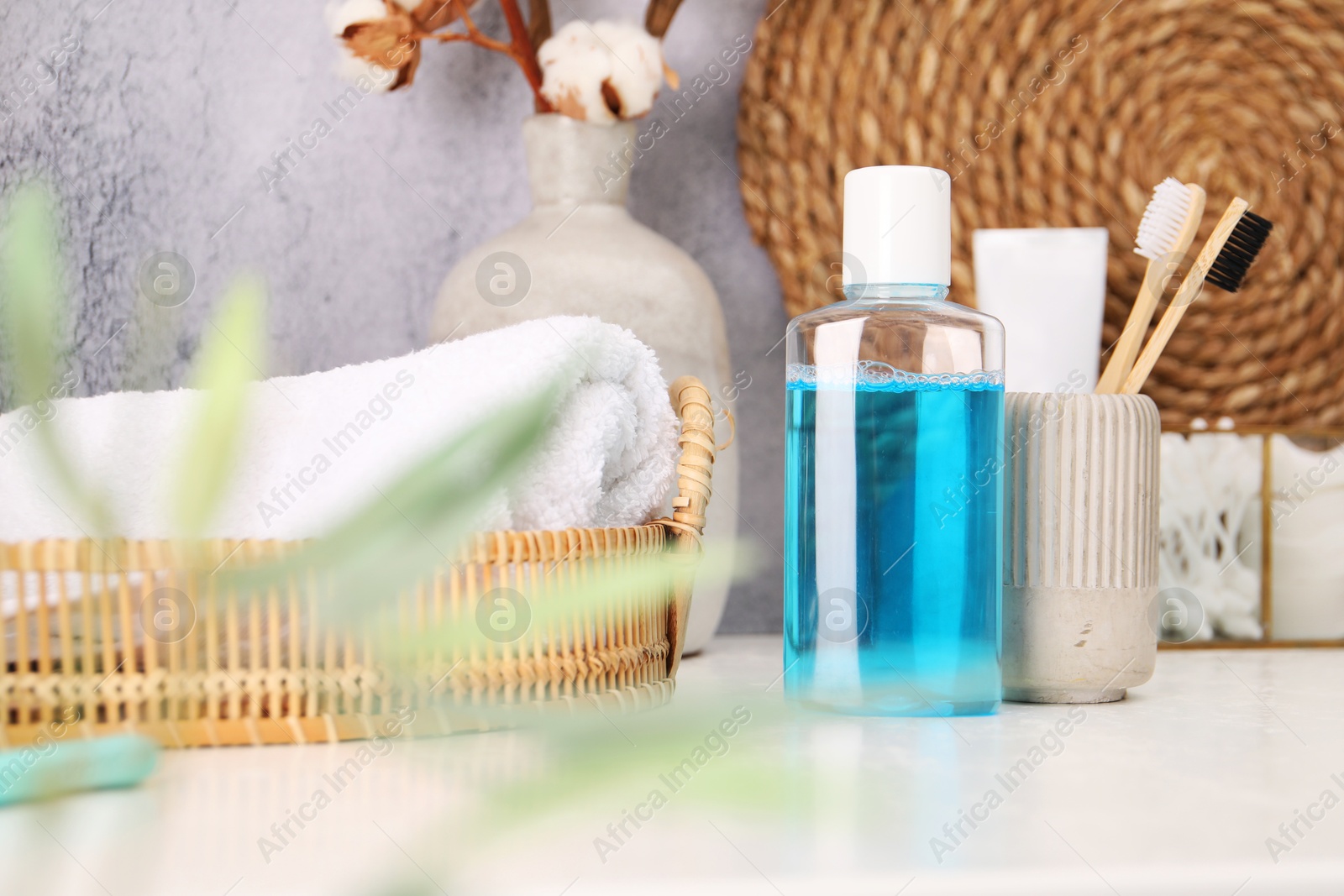 Photo of Bottle of mouthwash and toothbrushes on white table in bathroom