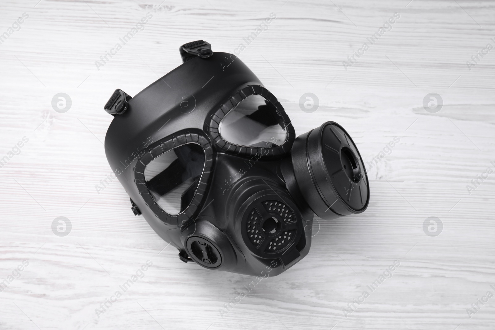 Photo of One gas mask on white wooden background, top view