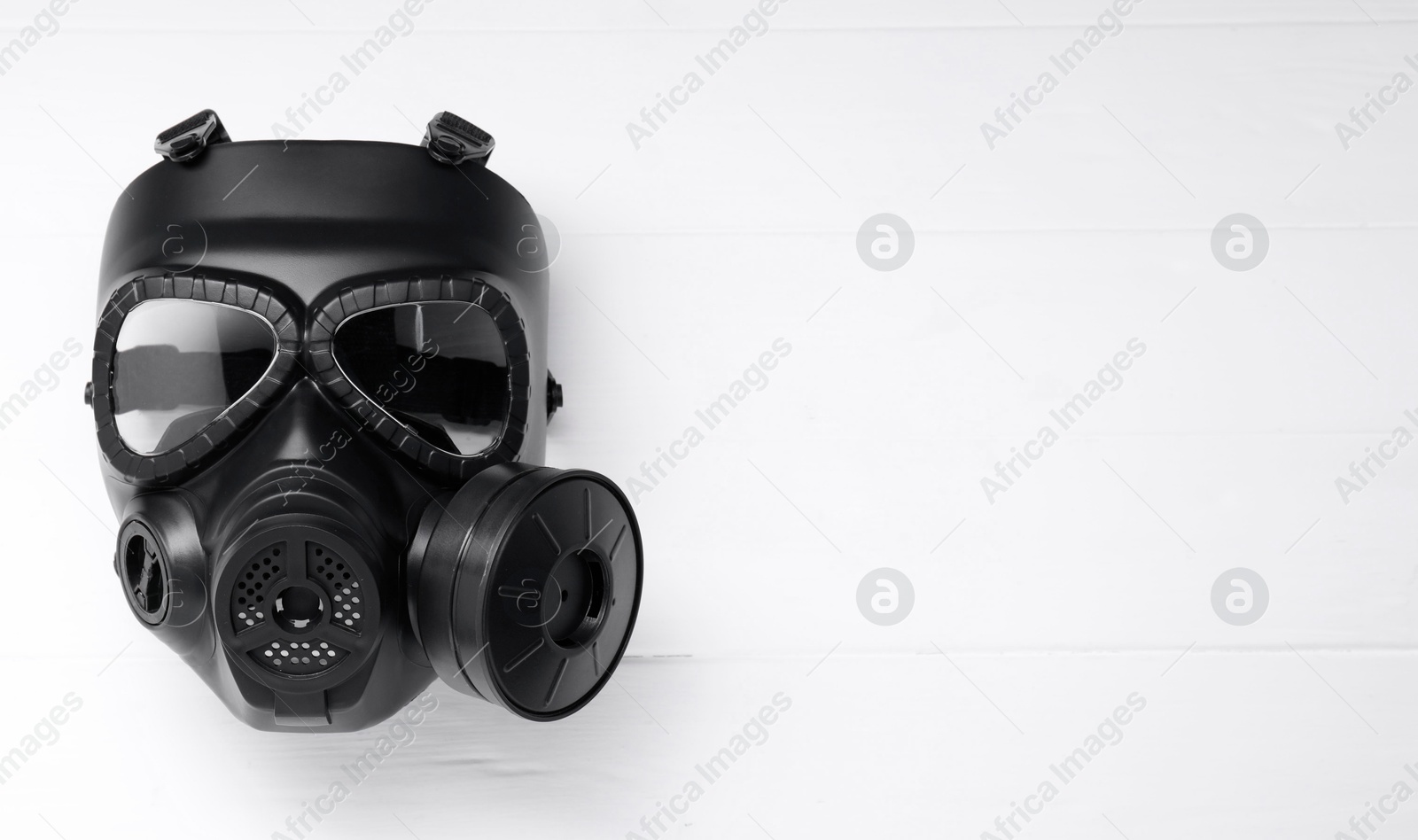 Photo of One gas mask on white wooden background, top view. Space for text