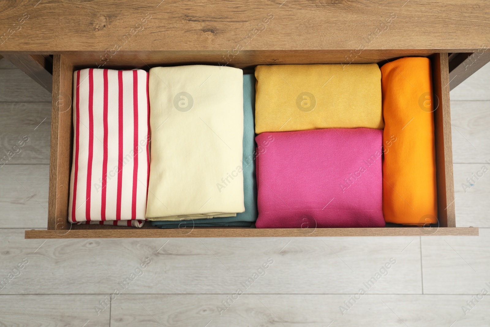 Photo of Wooden chest of drawers with different folded clothes indoors, top view