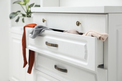 Cluttered chest of drawers indoors. Clothes in mess