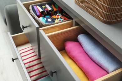 Chest of drawer with different folded clothes indoors, closeup