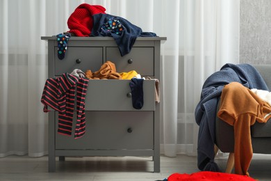 Room and dresser cluttered with clothes. Messy house