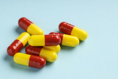 Photo of Many antibiotic pills on light blue background, closeup