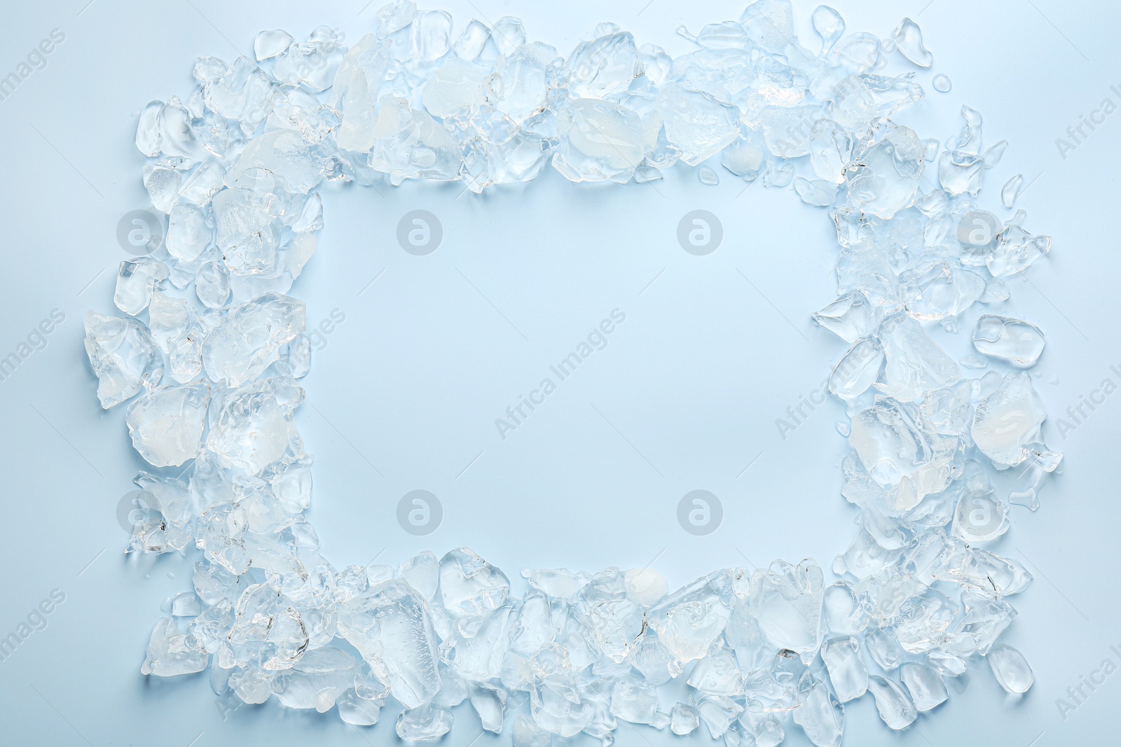 Photo of Frame of crushed ice on light blue background, top view. Space for text