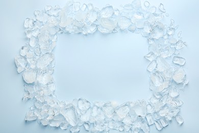 Photo of Frame of crushed ice on light blue background, top view. Space for text