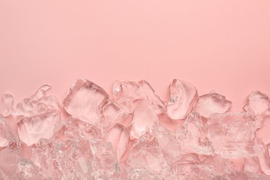 Photo of Pieces of crushed ice on pink background, top view. Space for text