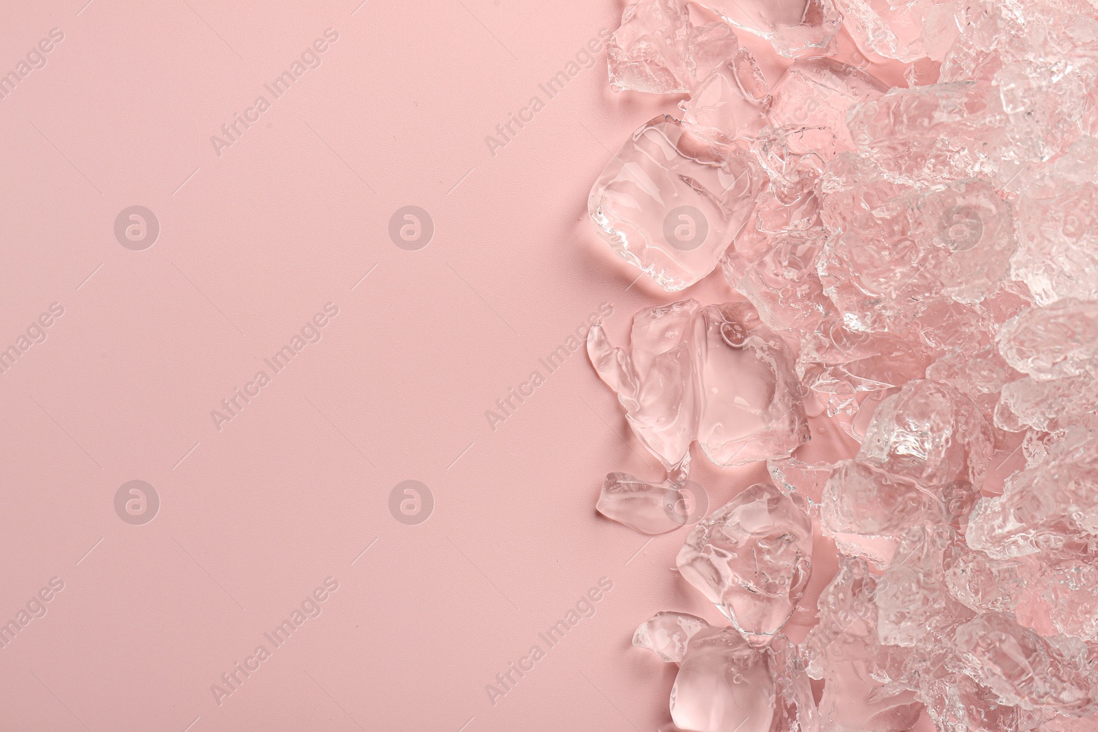 Photo of Pieces of crushed ice on pink background, top view. Space for text