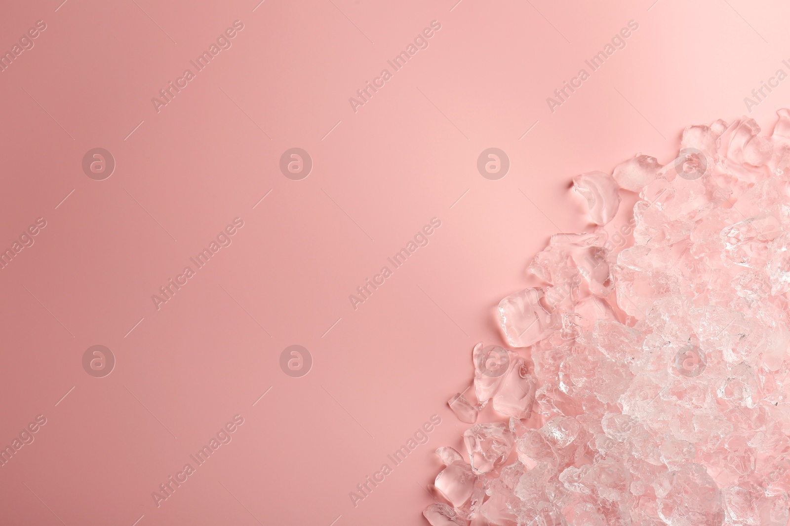 Photo of Pieces of crushed ice on pink background, top view. Space for text