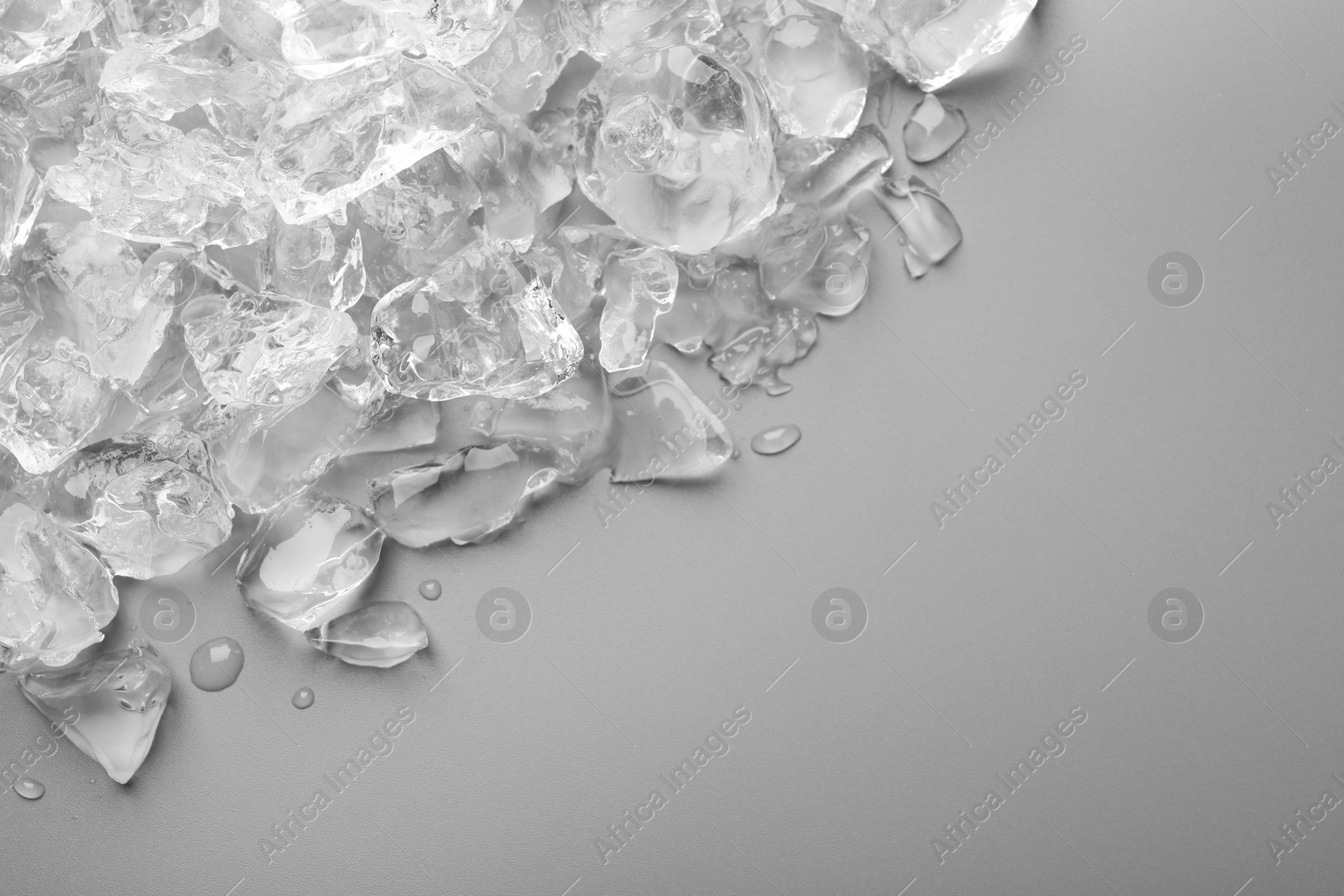 Photo of Pieces of crushed ice on grey background, top view. Space for text