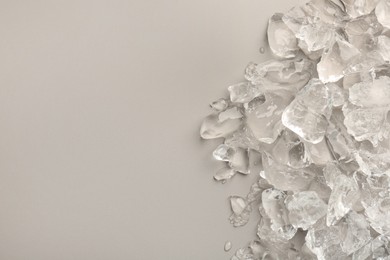 Pieces of crushed ice on grey background, top view. Space for text