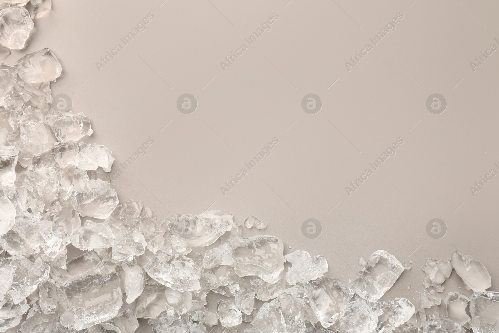 Photo of Pieces of crushed ice on grey background, top view. Space for text